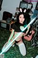 A woman in bunny ears holding a light saber.