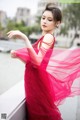 A woman in a red dress standing on a bridge.