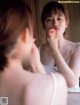 A woman brushing her teeth in front of a mirror.