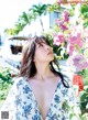 A woman standing in front of a bunch of flowers.