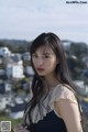 A woman with long black hair standing in front of a city.