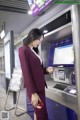 A woman in a red suit is using an atm machine.