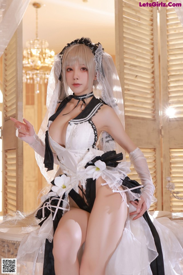 A woman in a wedding dress sitting on a bed.