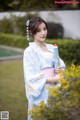 A woman in a blue and white kimono holding an umbrella.