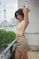 A woman in a beige shirt and polka dot skirt posing for a picture.