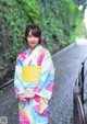 A woman in a colorful kimono standing on a bridge.